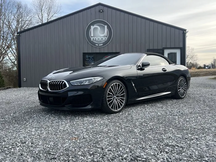 Black BMW 8 Series convertible with tinted windows outside the NU-Image shop