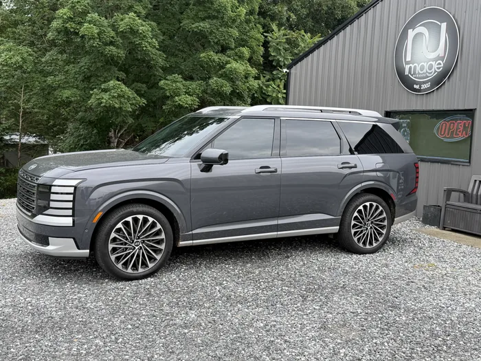 Grey Hyundai Palisade with tinted windows, side view at the shop